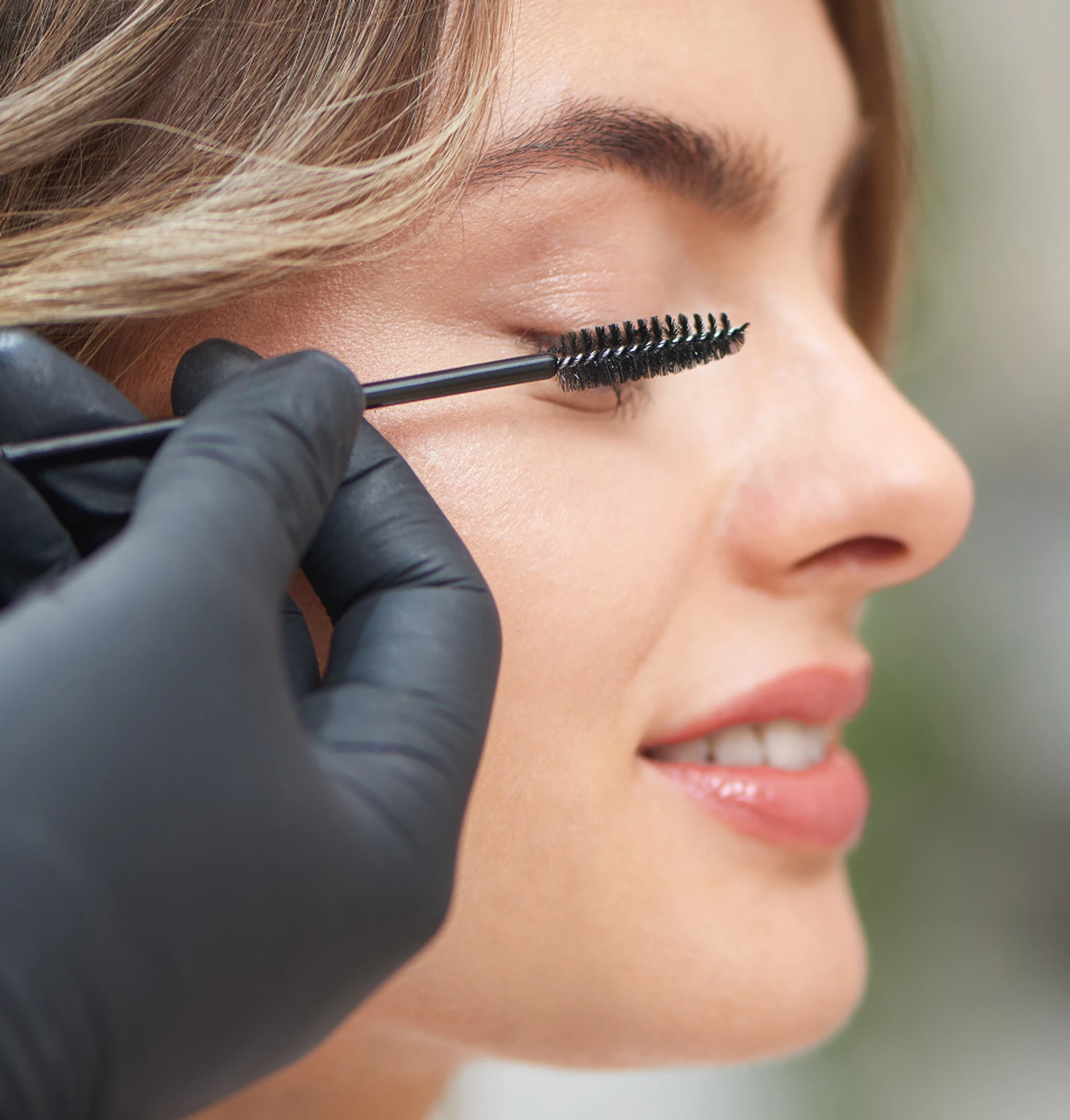 femme brossant les cils de sa cliente